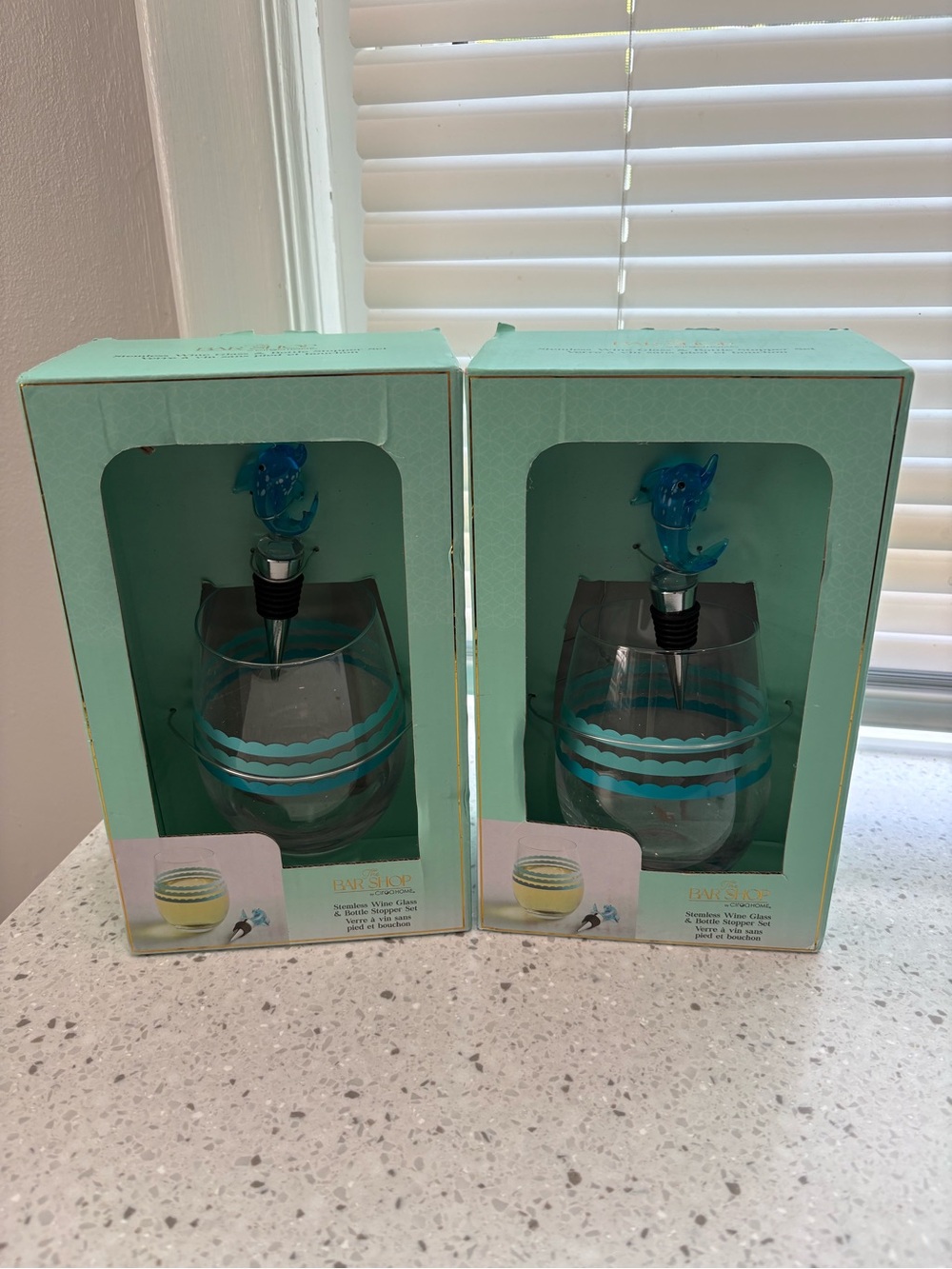 Ciroa Bar Shop stemless wine glass set w/ a blue dolphin-shaped bottle stopper.